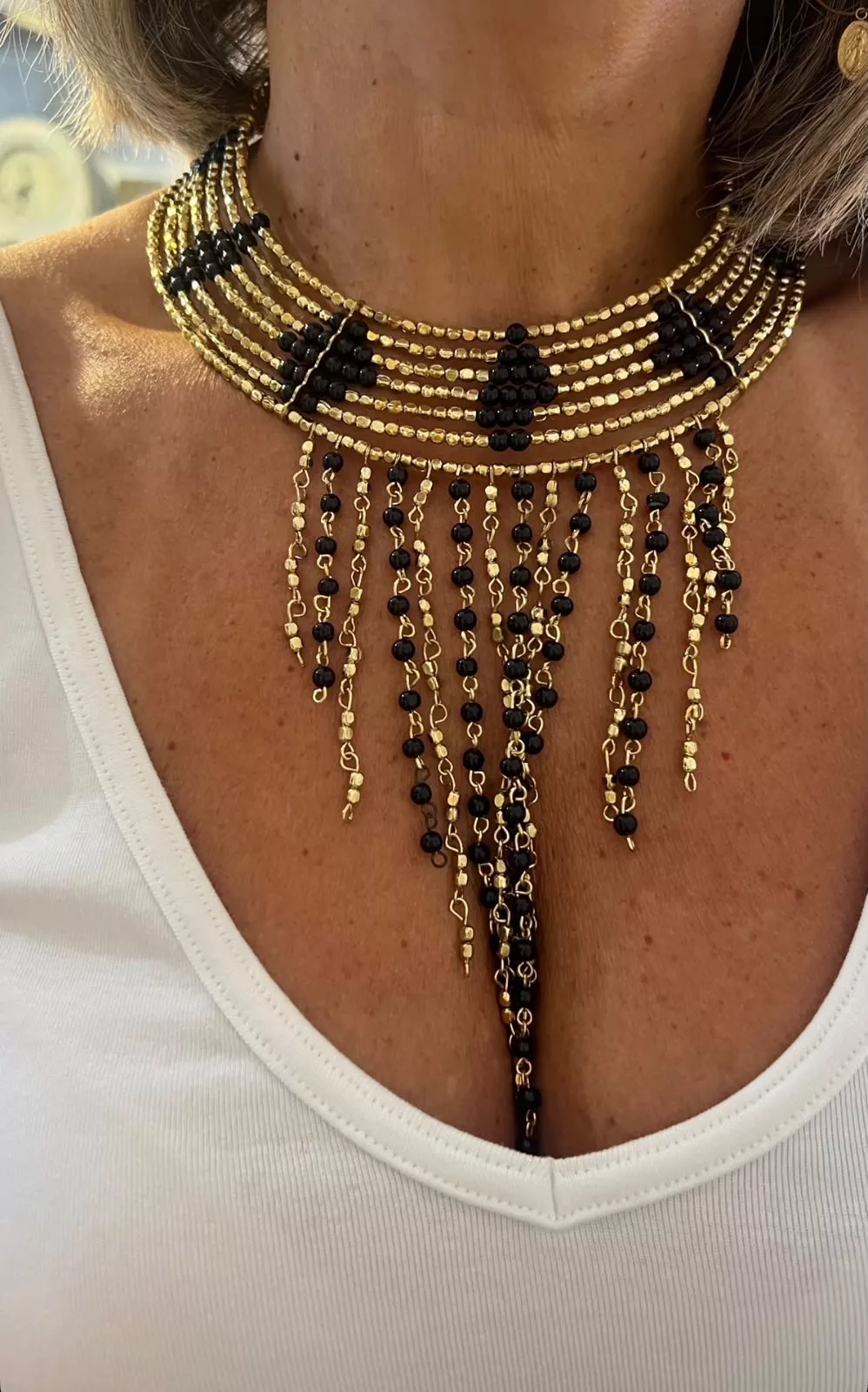 Colar de bijuteria indiana, com detalhes em dourado, elementos pretos e franjas decorativas. Uma peça marcante para dar personalidade a qualquer look!